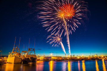 Fireworks celebration of long exposure over a calm fishing wharf
