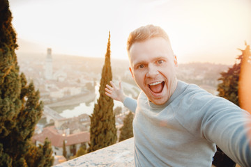 Happy man traveler taking selfie photo on city background Verona Italy sunset. Travel concept