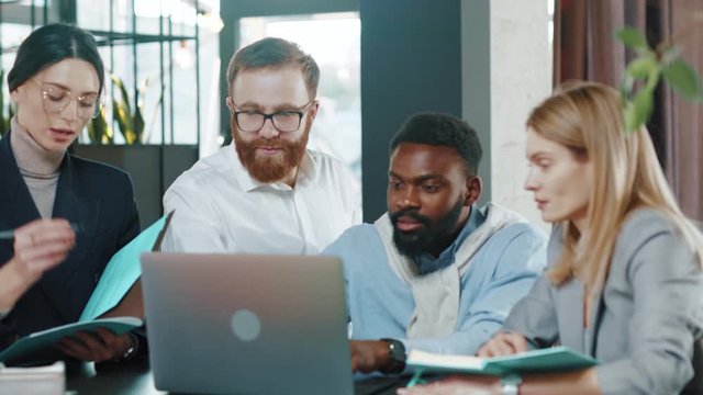 Shot of multi-ethnic co-workers gathered together working discuss current issues common tasks african team leader talk with colleague business workplace skilled technology slow motion
