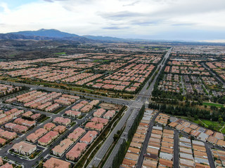 Aerial view of urban sprawl. Suburban packed homes neighborhood with road.during clouded day. Vast subdivision in Irvine, California, USA