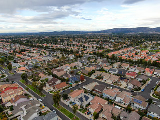 Fototapeta na wymiar Aerial view of urban sprawl. Suburban packed homes neighborhood with road.during clouded day. Vast subdivision in Irvine, California, USA