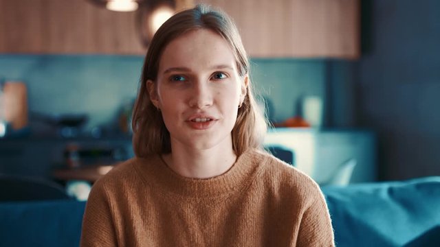 Pretty young redhead caucasian woman in the modern room looking and emotional talking at camera on different things making a blog.