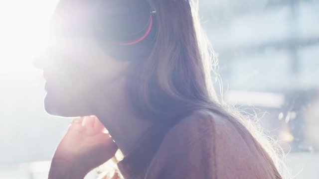 Happy charming redhair woman sitting on the floor near the window, listening music, dancing, smiling and having fun. Rays of the sun. Slow motion. Shoot on ARRI ALEXA.