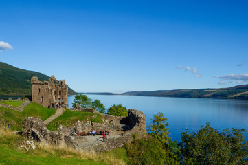 Fototapeta na wymiar Ruins of Urquhart Castle on the shores of Loch Ness in the Scottish Highlands, with a beautiful blue sky in the summer. Drumnadrochit, Inverness, Scotland