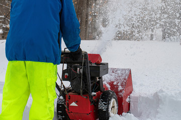 Man pushing snowblower during snowstorm