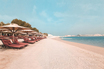 Vacation holidays beach background. The beach with sunbeds and sunshades in Dubai, on the shores of the Arabian Gulf.