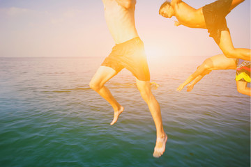 Group of happy crazy people having fun jumping in the sea water from boat. Friends jump in mid air on sunny day summer pool party at diving holiday. Travel vacation, friendship, youth holiday concept. - obrazy, fototapety, plakaty