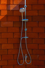 Shower head on red-brown brick walls for outdoor showers. Vintage shower head.