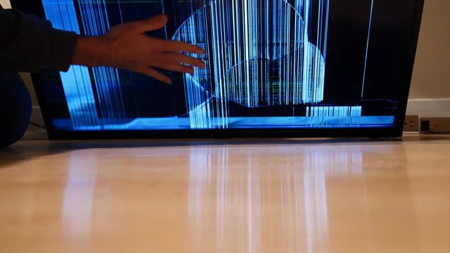 Pulling up a flat screen TV that felt on the ground and notice that the screen is smashed and broken.