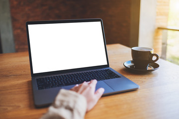 Mockup image of a woman using and touching on laptop touchpad with blank white desktop screen with coffee cup on wooden table