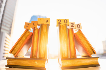 Happy New Year. Wood word number 2019 and 2020 on book with sun light, blurred city scape using as background holiday, education concept. 