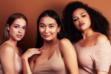 Obraz premium young pretty asian, caucasian, afro woman posing cheerful together on brown background, lifestyle diverse nationality people concept
