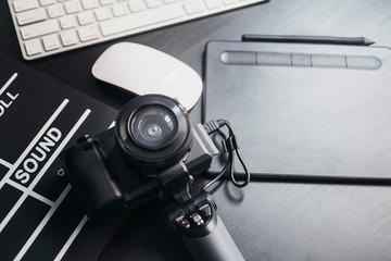 Professional photography equipment of Photographers.Mirrorless camera with lens, computer and Slate film, digital pen on wooden desk at studio selective focus
