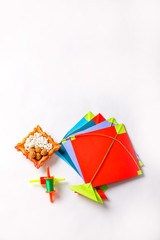 colorful paper kite with sesame seed ball or til ke laddo and tilgul in bowl on white background for indian festival makar sankranti 