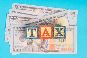 Income tax concept: TAX wordings on woodens blocks with US Dollar bills