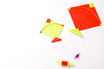 colorful paper kite with sesame seed ball or til ke laddo and tilgul in bowl on white background for indian festival makar sankranti 