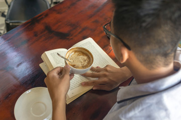 Man drinking cup of Cappuccino and reading book