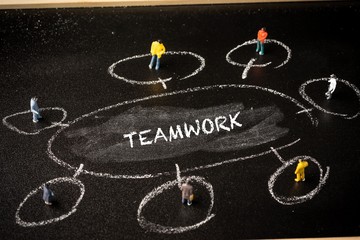 Business concept: Teamwork. A group of miniatures person on a chalkboard with "TEAMWORK" wordings