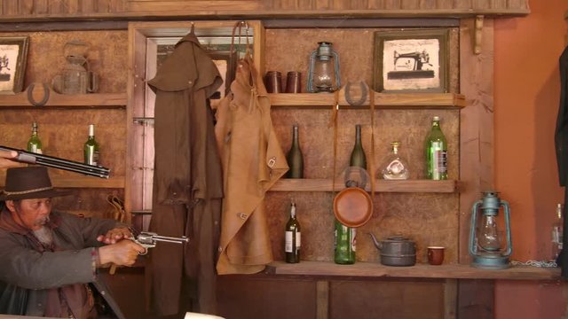 Two Asian cowboys shooting rifle and revolver gun in the couter saloon whisky bar and point the weapon left and right.