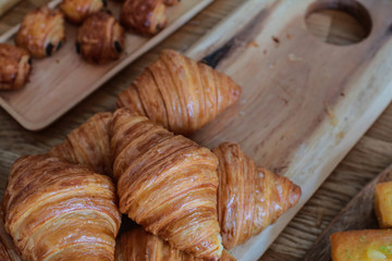 freshly baked croissants on wooden cutting board Warm Fresh Buttery Croissants and Rolls. French and American Croissants and Baked Pastries