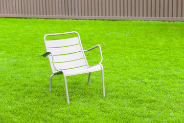 Garden chair for relaxing on the green grass on the background of the fence.