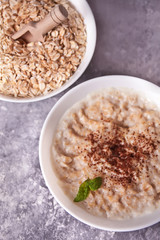 Oatmeal porridge in the white bowls on the concrete table. Health breakfast. Close up