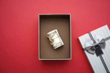 A lovely gift box on red background with a dollar bills inside