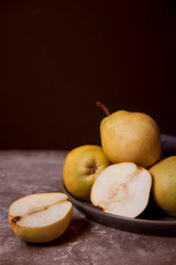 Ripe pears in a plate on dark background