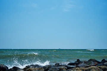 Image of the sea shore. In the background is a warship.