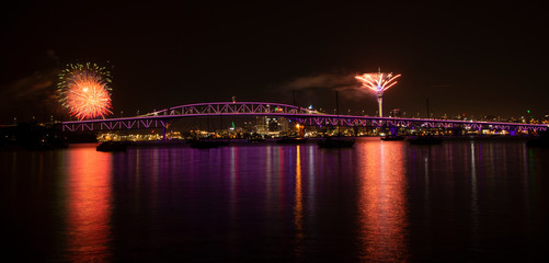 Auckland fireworks for New Year celebration with Harbor Bridge illuminated in purple