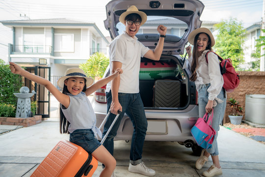 Portrait Of Asian Family With Father, Mother And Daughter Looks Happy While Preparing Suitcase Into A Car For Holiday. Shot In The House Garage..