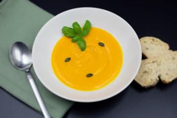 fresh pumpkin soup in plate on green napkin with blurred background.
