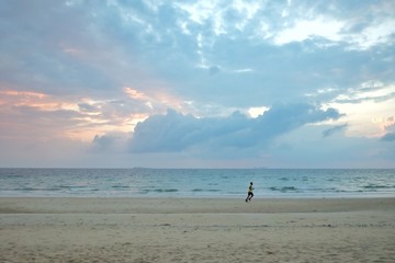 Colorful blue sky with fluffy clouds at dusk and sea view,blurred a man running along the beach