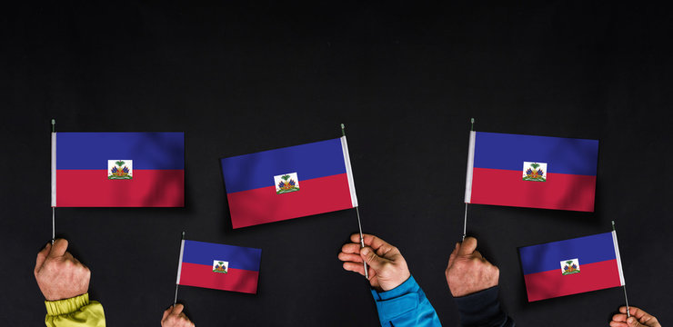 Hands holds flags of Haiti  on dark background