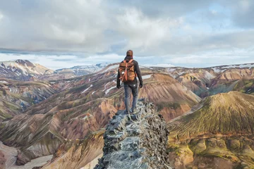Poster adventure travel, hiking in Iceland with backpack, tourist looking at colorful landscape of Landmannalaugar © Song_about_summer