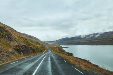 travel background, beautiful asphalt road in fjords in Iceland, cloudy landscape, roadtrip in autumn