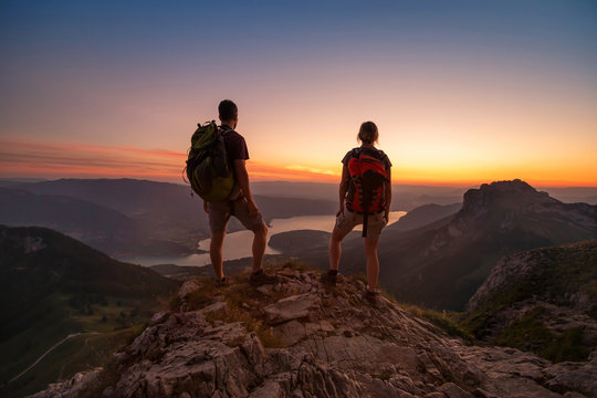 travel to Alps mountains, tourists hikers with backpacks at sunset enjoying panoramic view