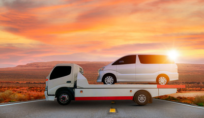 Obraz premium Tow truck delivers the damaged vehicle, Sun light flare.