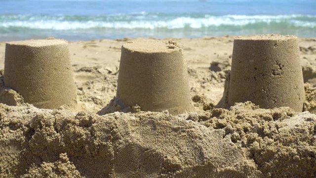 Closeup of sandcastles on the sand of a beach, with the mediterranean sea in the background. Summer and vacations concept.
