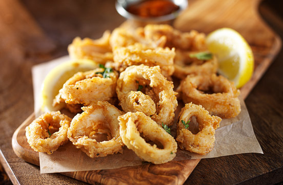 fried calamari squid appetizer on wooden serving tray