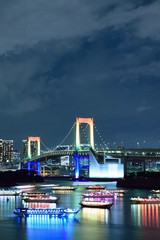 Urban landscape of Tokyo Rainbow bridge with illuminated tourist boats 