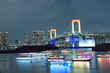 Fototapeta na wymiar Urban landscape of Tokyo Rainbow bridge with illuminated tourist boats 