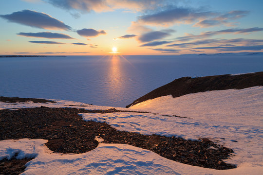 Spring arctic landscape with the midnight sun and the coast of the Arctic Ocean. North of the Arctic Circle at the end of May, the sun does not set at night over the horizon. Pevek, Chukotka, Russia.
