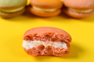 half eaten pink macaroon on yellow with some macaroon on back