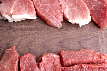 Large slices of beef and pork on an old wooden surface. Raw meat before cooking. The concept of cholesterol food. Copy space.