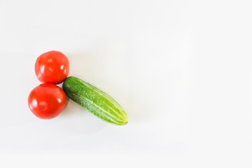 Red ripe juicy tomatoes and green cucumber. The phallic image of natural components. Light gray background