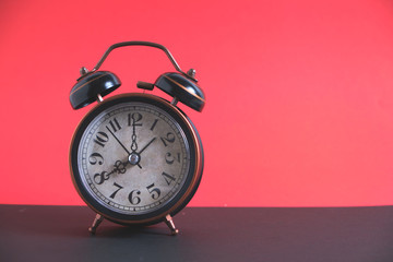 Old, vintage retro alarm clock on a bright red background.