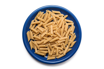 Closeup of uncooked organic penne rigate pasta in blue plate on white background. Slow carbs concept. Top view