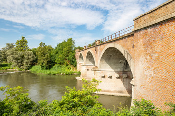 Fototapeta na wymiar old railway bridge over Lambro river next to Lambrinia village (Chignolo Po), Province of Pavia, Lombardy, Italy