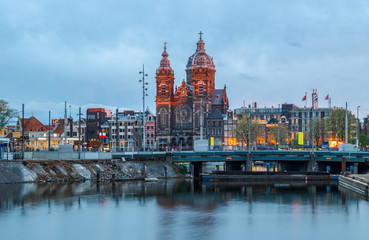 Obraz premium Scenic view of Basilica of Saint Nicholas and skyline of the the old city district reflected in the water of the canal. Blue hours, Amsterdam, Netherlands.